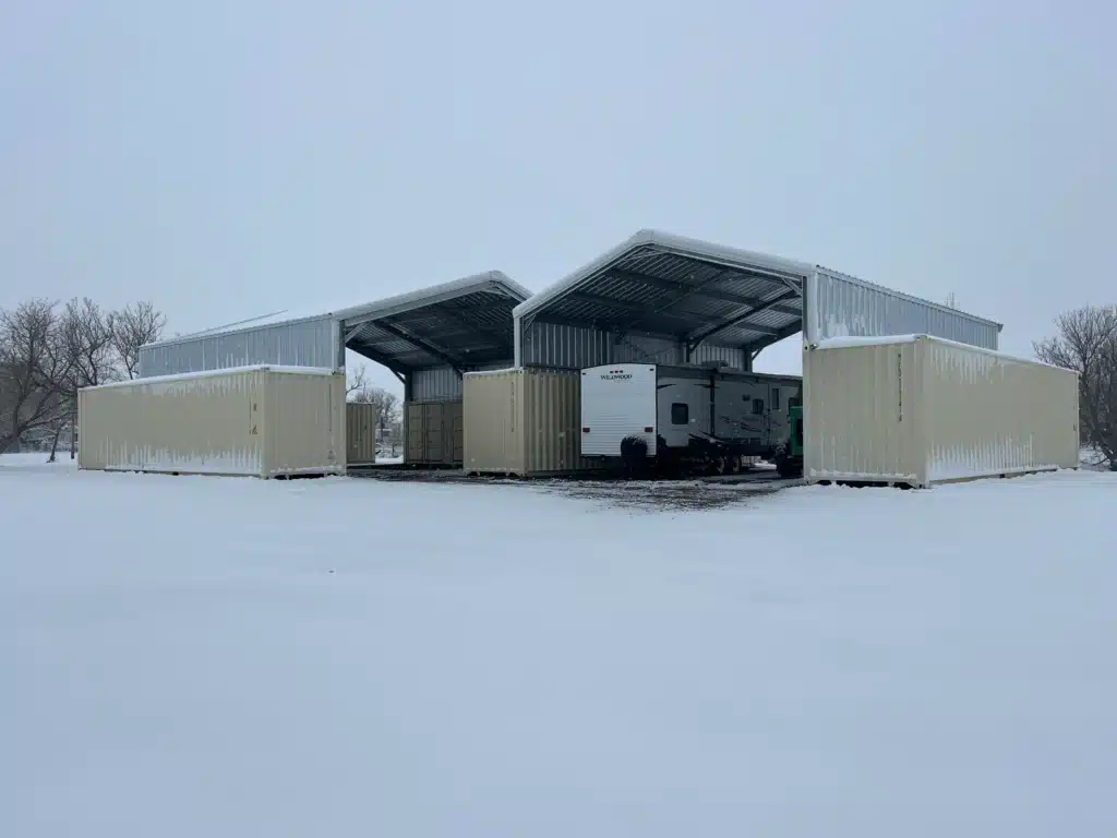 Steel gable roof container cover sheltering RV in snow